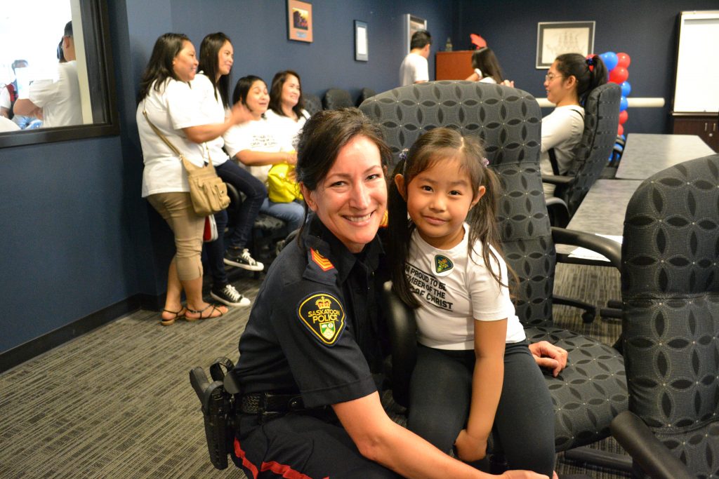 A police officer and an INC Giving volunteer take a photo together.